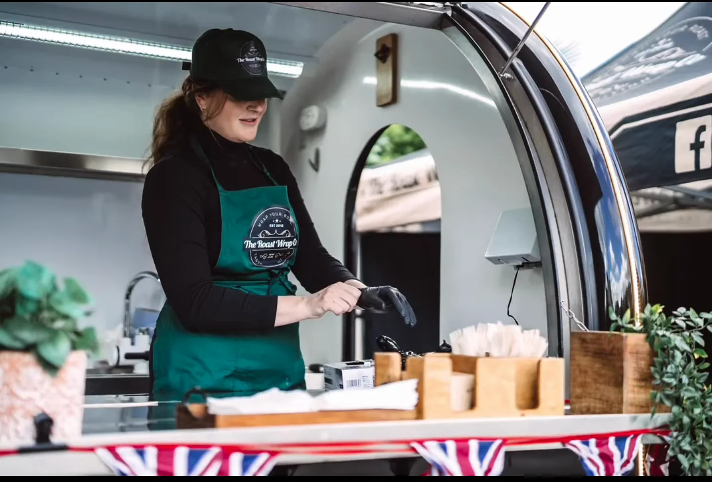 A member of The Roast Wrap Co. team serving from the mobile catering trailer